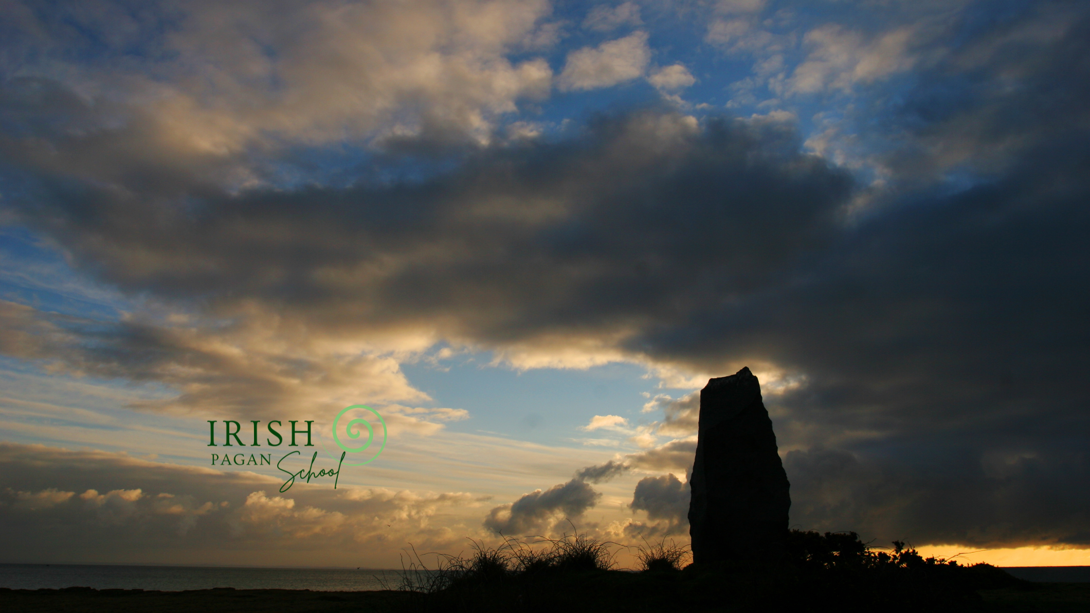 Silhouetted standing stone against a dramatic evening sky with clouds, representing the mystery of Crom Cruach in Celtic and Irish mythology, with the Irish Pagan School logo in the foreground.