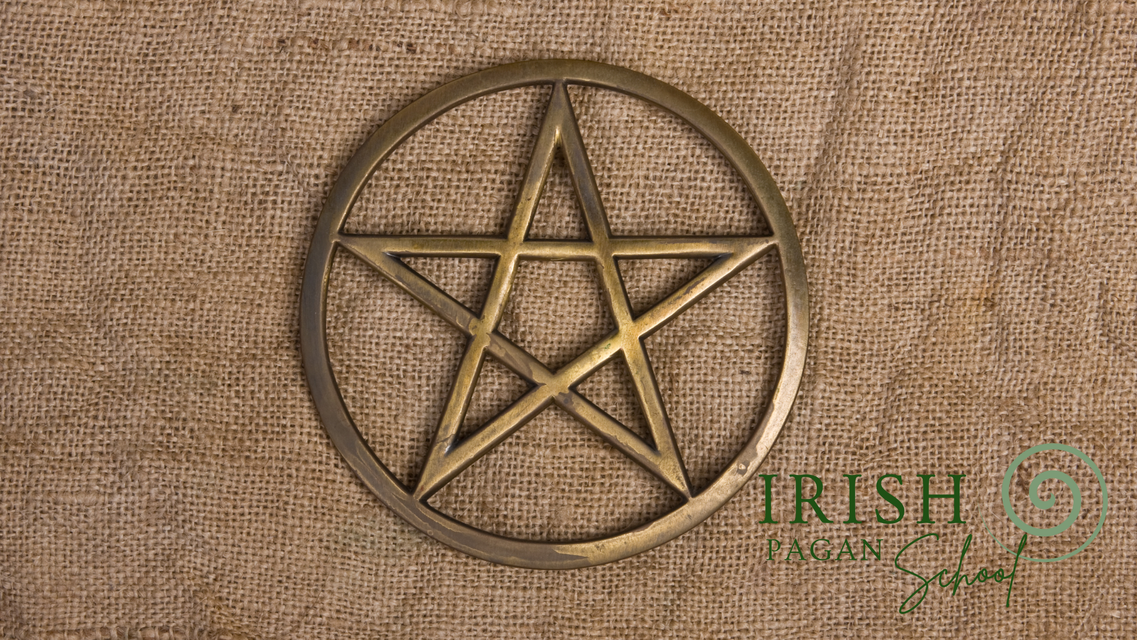 A brass pentacle symbol representing modern pagan religion, placed on a textured burlap background. The Irish Pagan School logo is visible in the lower right corner. This image accompanies the blog post A History of Pagan Religion: The Roots of NeoPaganism, which explores the origins and evolution of contemporary pagan spirituality.